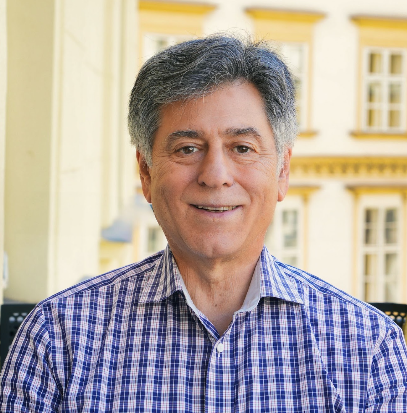 Photo of André Goodfriend from shoulders up in a blue plaid shirt with a building in the background